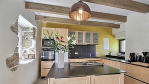 A modern kitchen with wooden cabinets, a central island, and a hanging light fixture. - Kerguntuil - Pleumeur Bodou (PLEUMEUR BODOU)