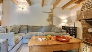 A cozy living room with a sofa, wooden coffee table, and stone wall. - Kerguntuil - Pleumeur Bodou (PLEUMEUR BODOU)