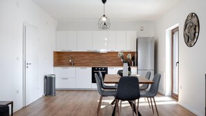 A modern kitchen with white cabinets, a wooden countertop, and a dining area with a table and chairs. - Lovely apartment in Brodarica with WiFi (Brodarica)