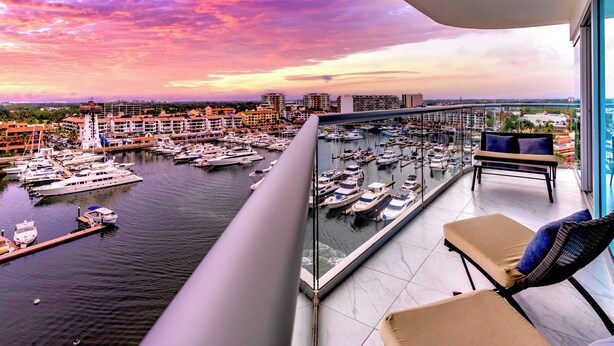 A balcony with a view of a marina and cityscape during sunset.