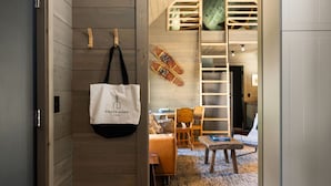 Un intérieur en bois agrémenté d’un sac fourre-tout blanc suspendu, d’une échelle et d’un coin salon confortable.