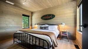 Une chambre aux murs lambrés, avec un lit, des lampes de chevet et un motif décoratif représentant des poissons sur le mur.