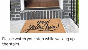 Una escalera que lleva a una puerta con felpudo que dice "¡genial, ya llegaste!".