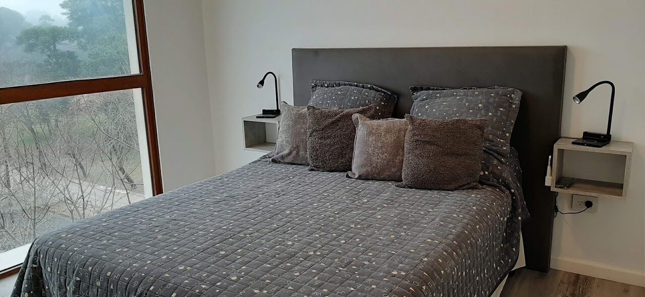 Une chambre à coucher avec un grand lit, deux tables de chevet et une fenêtre donnant sur des arbres.