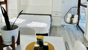 Una habitación moderna con una cama, una mesa de comedor con frascos, una silla y una ventana.