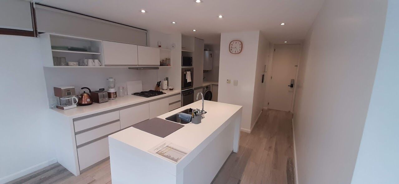 A modern kitchen with white cabinetry, a central island, and built-in appliances.