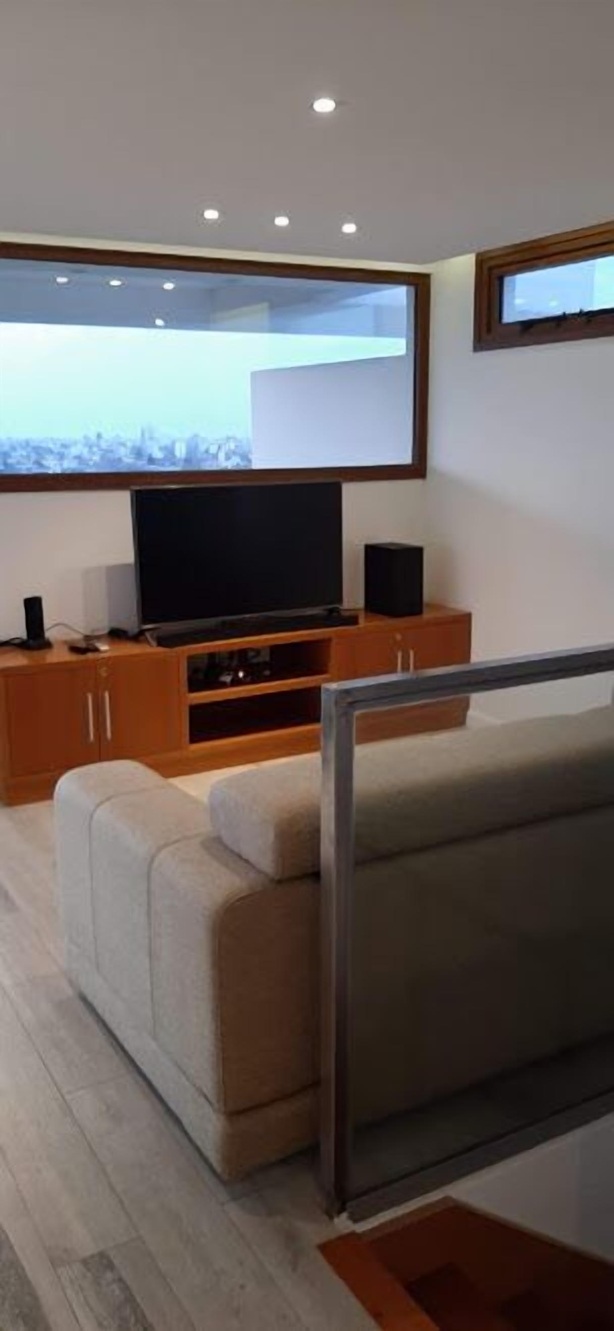 A modern living room with a flat-screen TV, wooden cabinets, and a sofa.