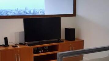 A modern living room with a flat-screen TV, wooden cabinets, and a sofa.