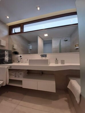 Un baño moderno con un espejo grande, un lavabo blanco y un perchero para toallas.