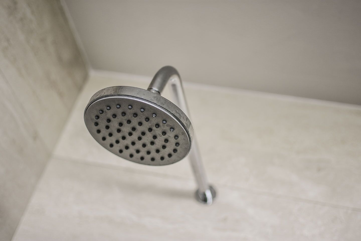 A showerhead with a round, perforated design, mounted on a wall with a simple, clean background.