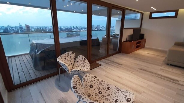 Una sala moderna con un amplio ventanal corredera que da a un balcón con vistas a la ciudad.