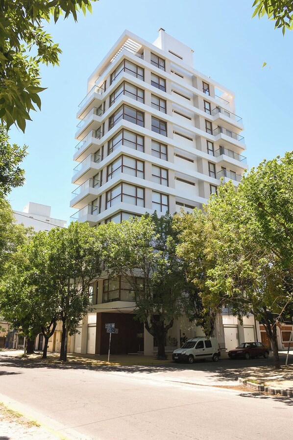 Un edificio de varios pisos con un diseño arquitectónico moderno, que presenta balcones y ventanas amplias.