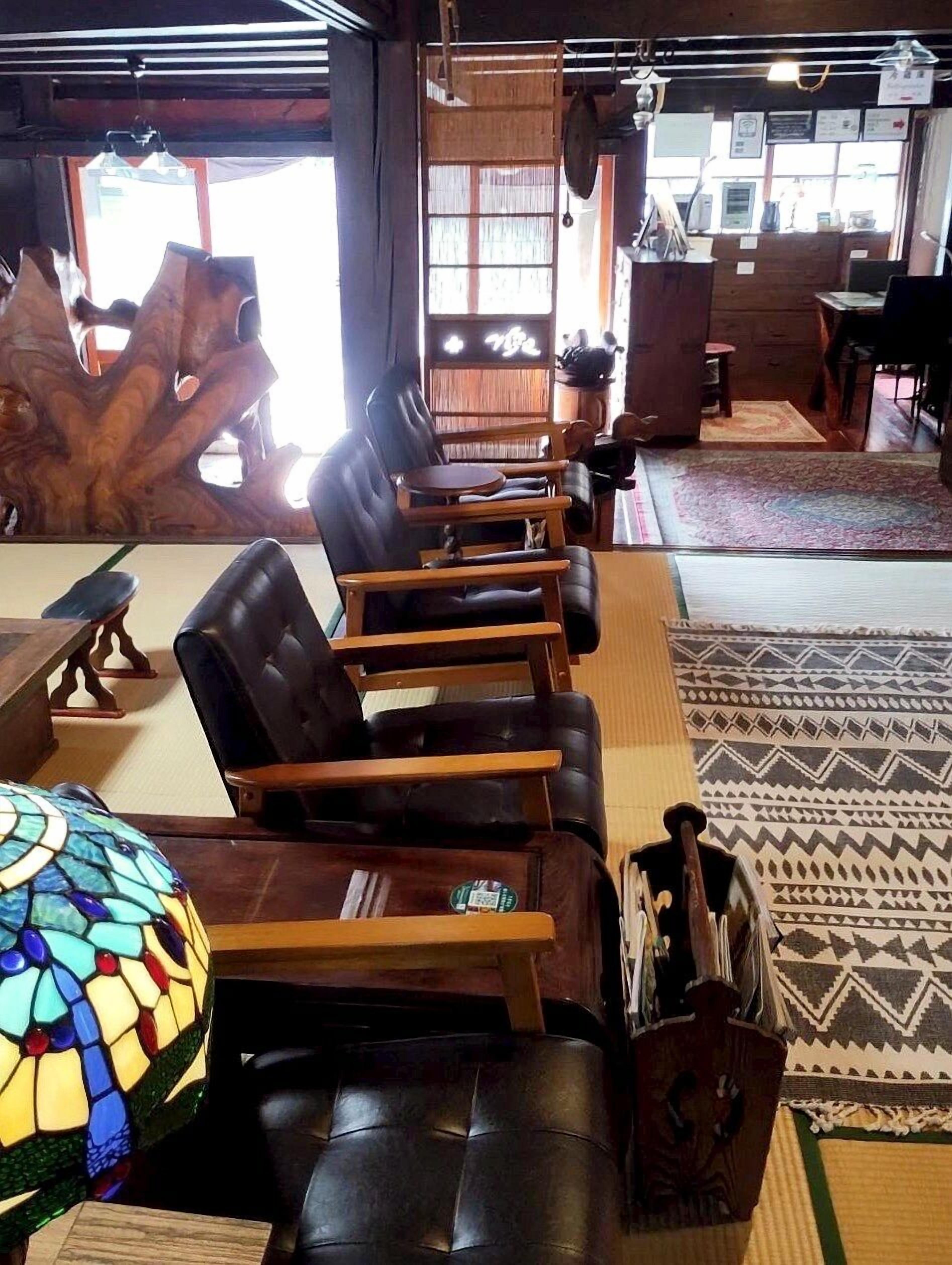 A room with a wooden reception desk, a large wooden sculpture, and a seating area with leather chairs and a wooden table.