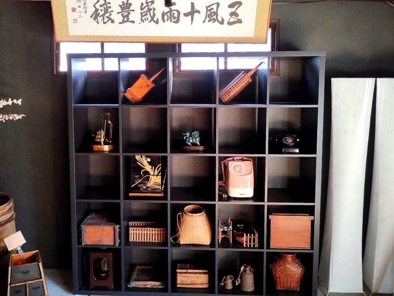 Une collection d’objets anciens exposés dans une étagère noire.