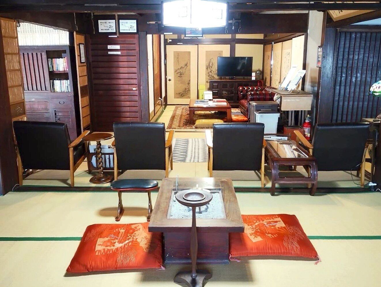A traditional Japanese-style room with tatami flooring, a low table with a tea set, and a television.