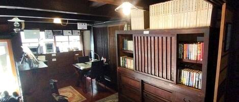 A room with a wooden bookshelf, a desk with a chair, and a small rug on the floor.