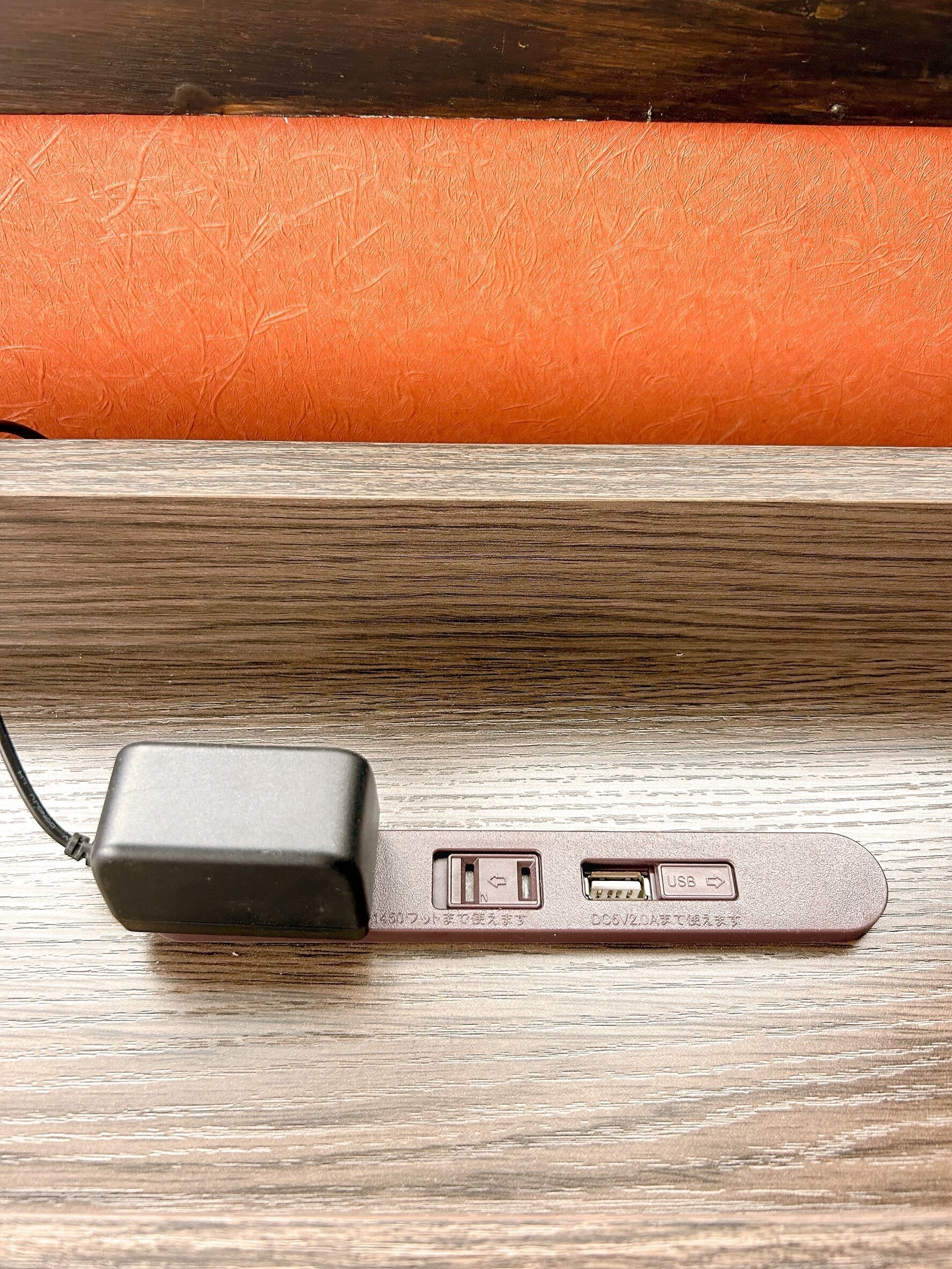A power adapter with USB ports on a wooden surface.