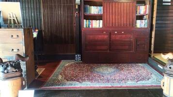A room with a wooden wardrobe, a small bookshelf, a rug, and a wooden cabinet with a handle.