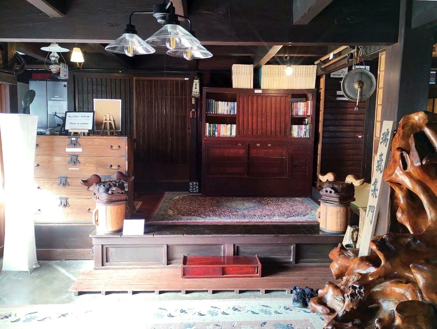 A traditional Japanese room with a tatami mat floor, a low wooden bench, a bookshelf, and a wooden cabinet.