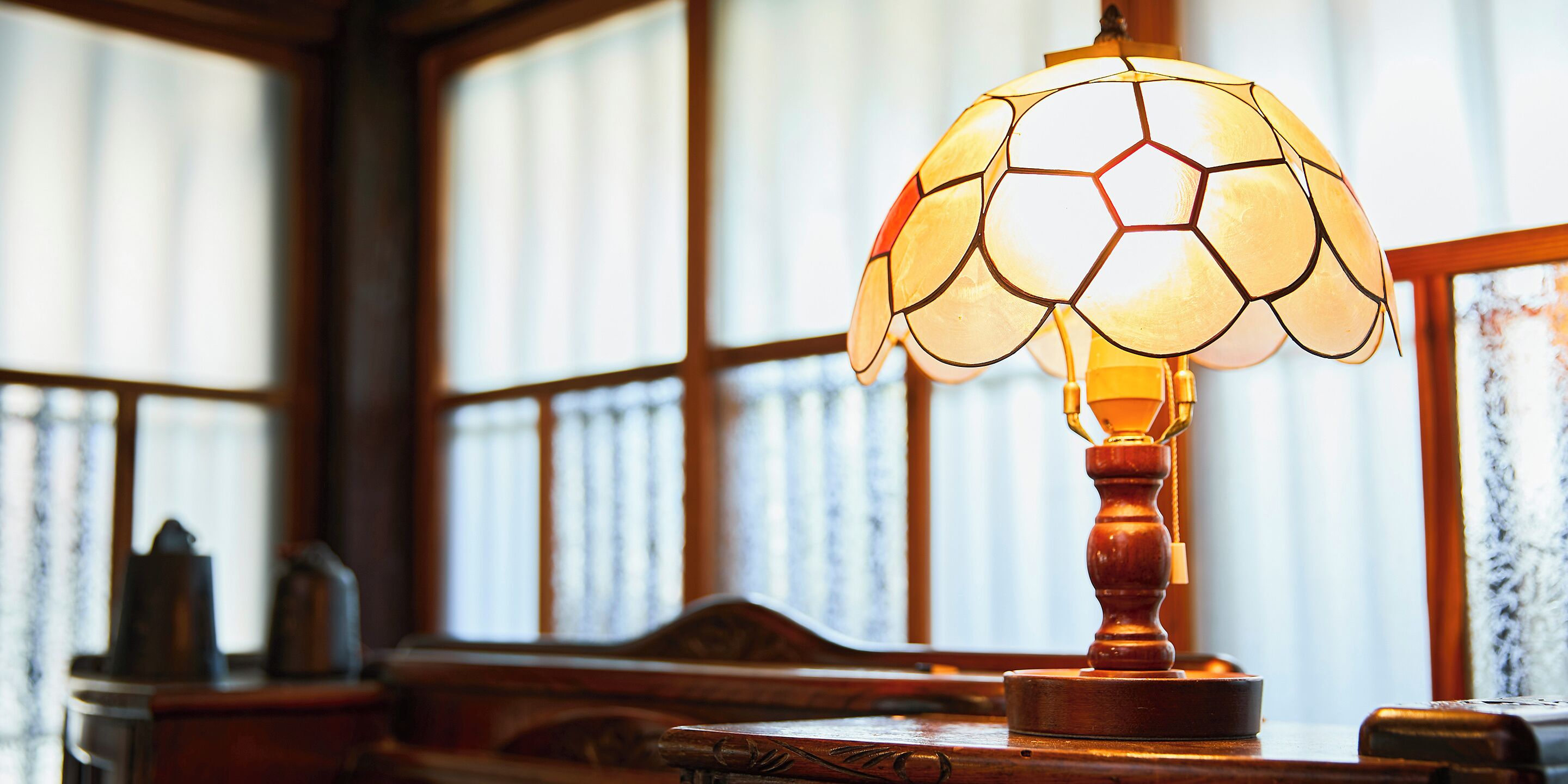 Una lámpara con diseño de balón de fútbol sobre una mesa de madera en una habitación con ventanas amplias.