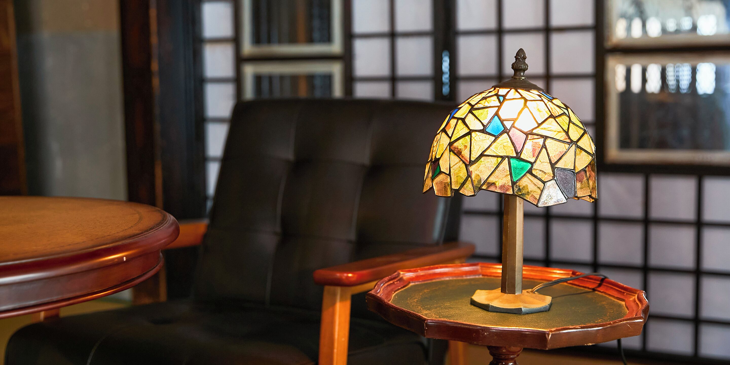 A table lamp with a stained glass shade on a wooden table.