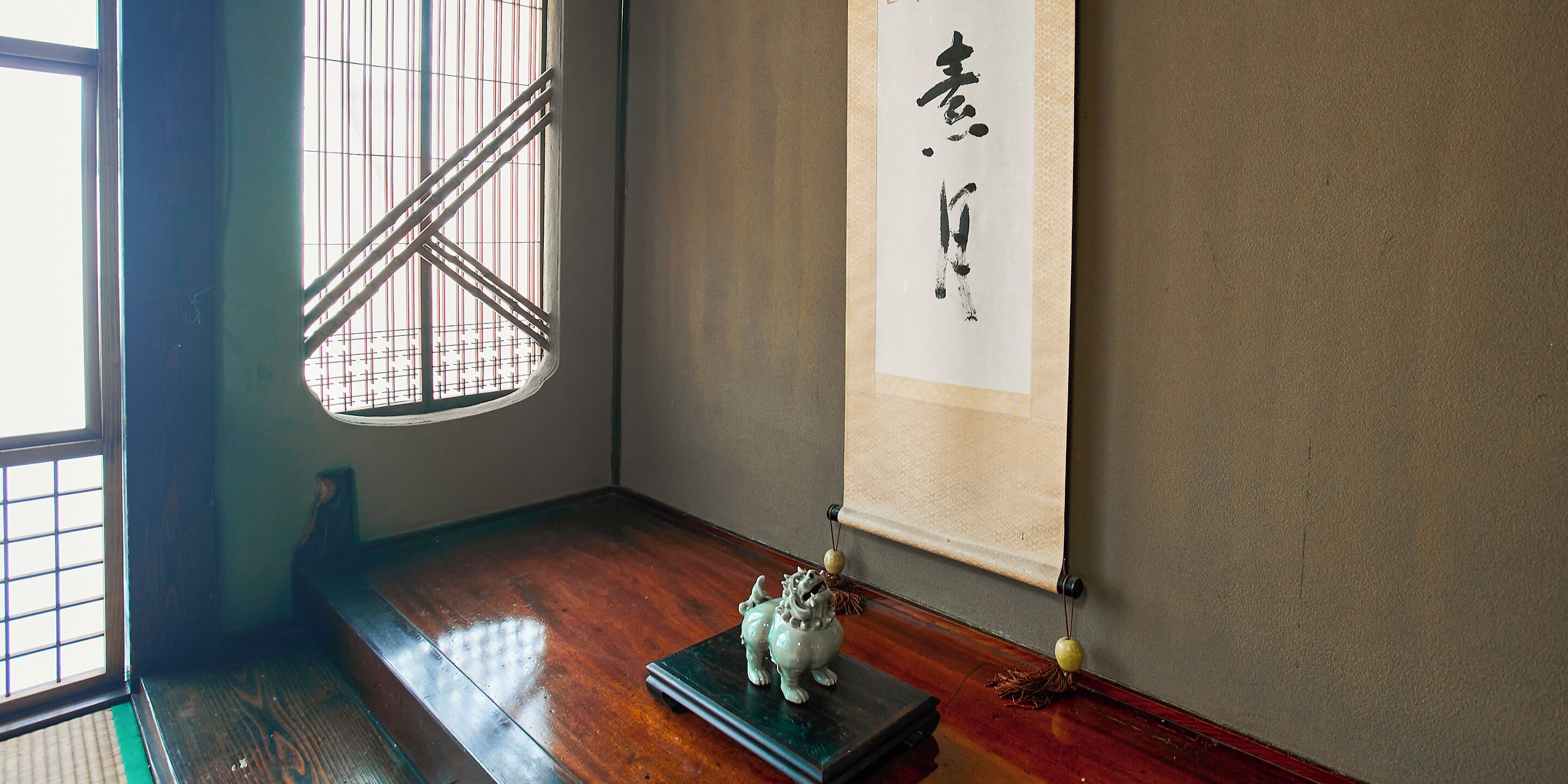 A traditional Japanese room with tatami flooring, a shoji screen, and a calligraphy scroll.