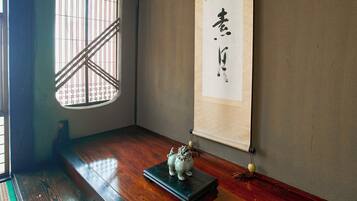 A traditional Japanese room with tatami flooring, a shoji screen, and a calligraphy scroll.
