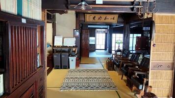 A traditional Japanese room with tatami mats, a shoji screen, and a wooden desk with a computer.