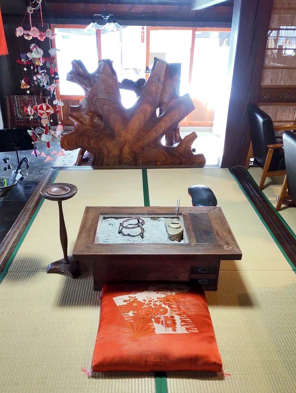 A tatami mat room with a traditional Japanese tea ceremony setup, including a tea caddy and a cushion.