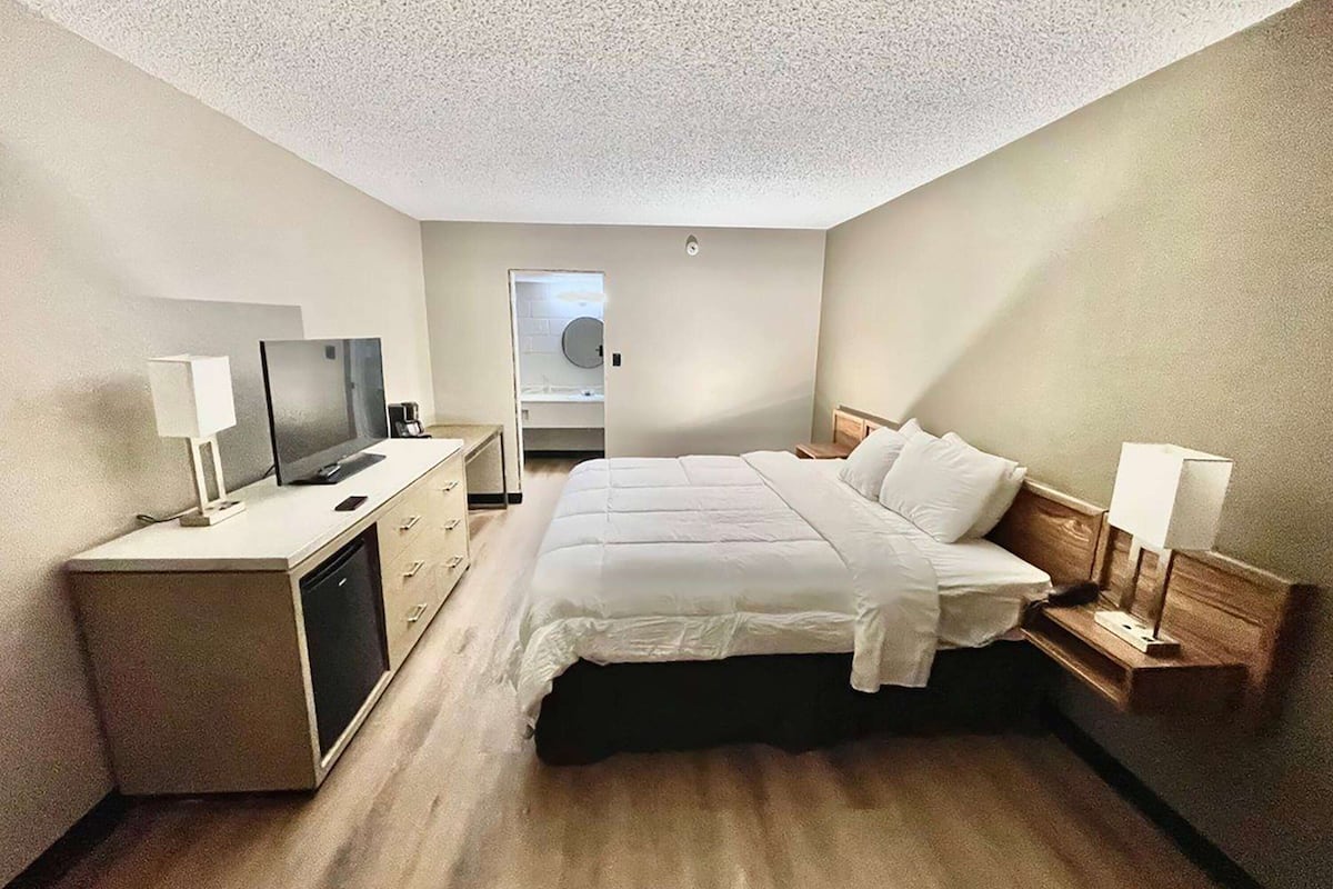 A hotel room with a bed, a TV, a desk, and a mirror.