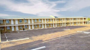 A motel with multiple rooms, a parking lot, and a flat roof.