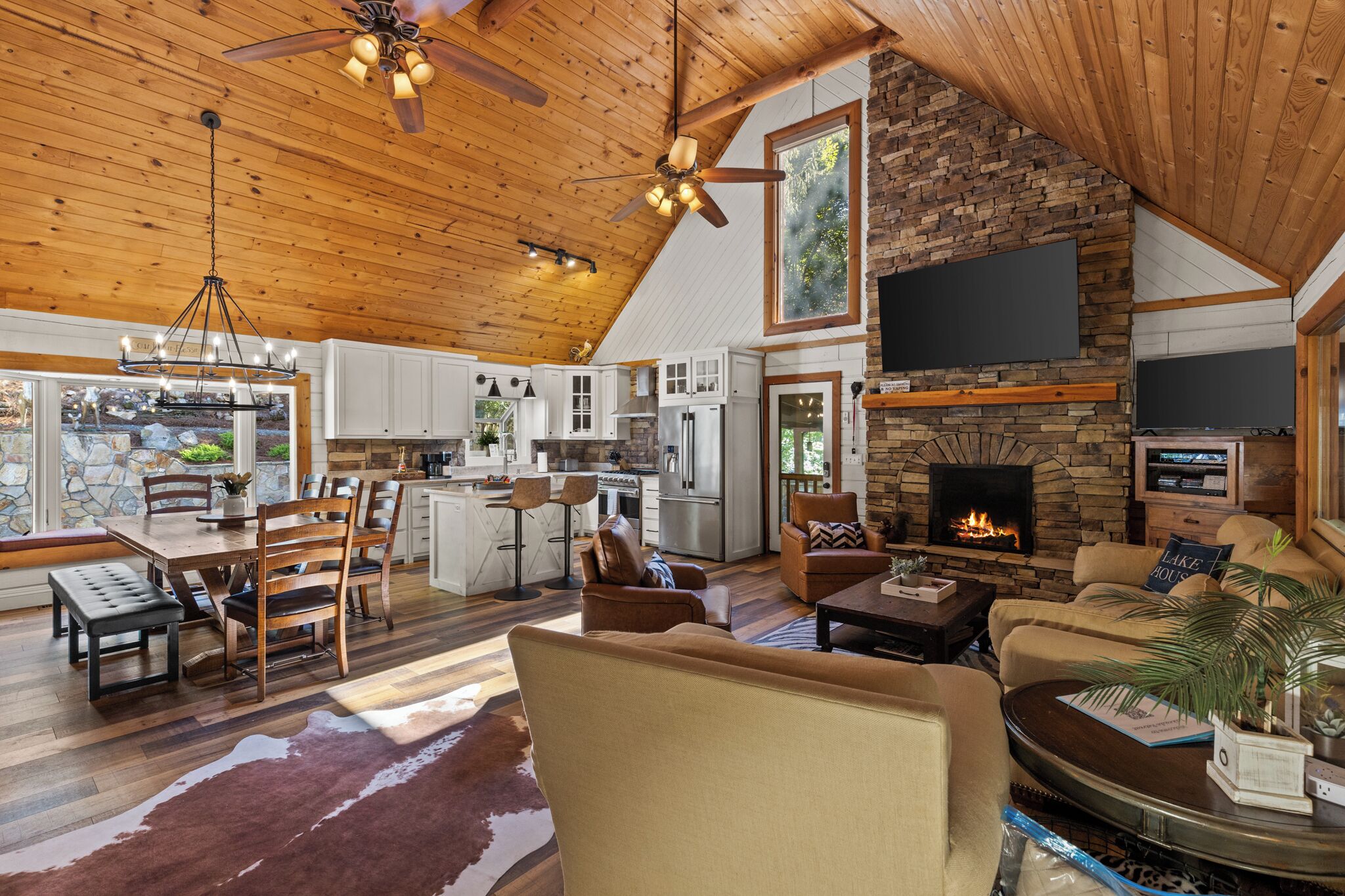 A spacious living area with a fireplace, wooden ceiling, and a stone wall.