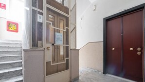 A hotel entrance with a metal gate, a wooden door, and a staircase leading to an upper floor. - Sleek City Oasis - City Centre (Cagliari)