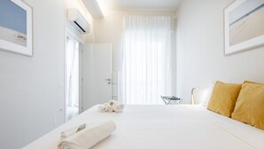 A hotel room with a bed, a chair, a table, and a window with curtains. - Sleek City Oasis - City Centre (Cagliari)