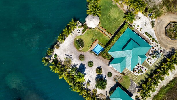 Vue aérienne d’un complexe hôtelier doté d’une grande piscine, de nombreuses chambres et d’un aménagement paysager luxuriant.