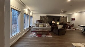 Un salon spacieux doté d’une grande fenêtre, d’un canapé, d’une table basse et d’un coin repas avec des chaises et une table.