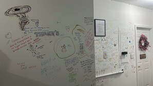 Un mur recouvert de divers messages manuscrits, de dessins et d’une photographie encadrée.