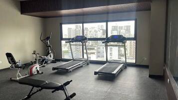 Un gimnasio con cintas de correr, una banca y máquinas de pesas.