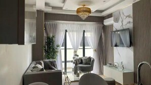 A modern living room with a sofa, armchairs, a dining table, and a TV mounted on the wall. - Best Apartment in Downtown (Santo Domingo)