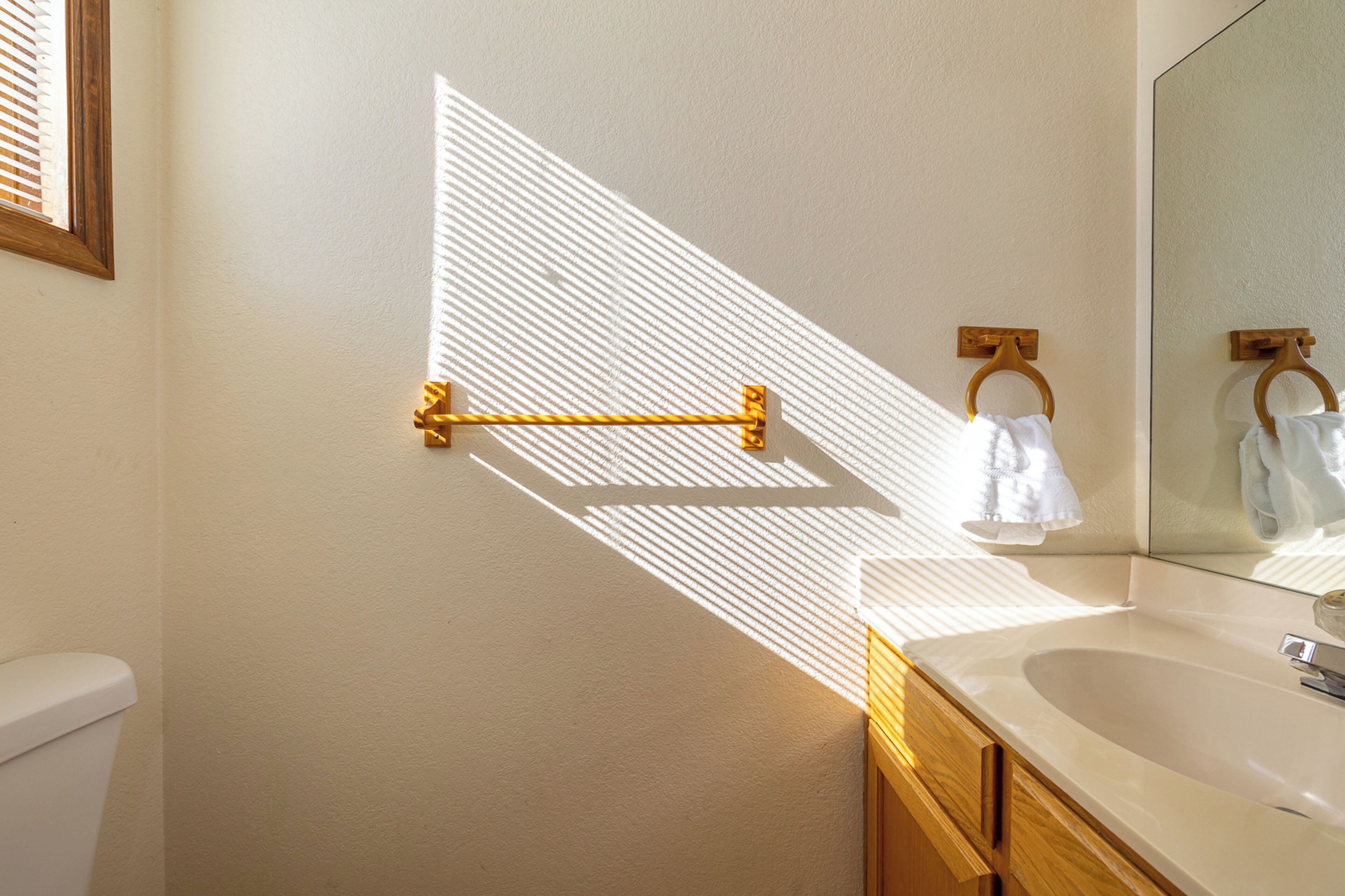 A bathroom with a white sink, wooden cabinet, and a towel rack.