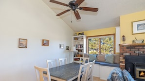 A dining area with a wooden table and chairs, a built-in bookshelf, and a fireplace. - Bear Paw (Flagstaff)