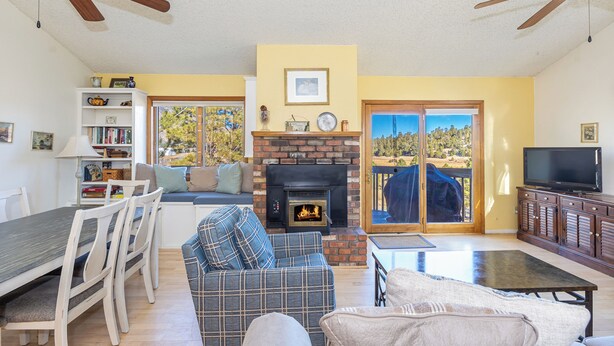 A living room with a fireplace, a television, and a dining area with chairs and a table. - Bear Paw (Flagstaff)