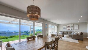 Un vaste espace de vie comprenant une grande table à manger en bois, des sièges confortables, un canapé et une vue sur l’extérieur.