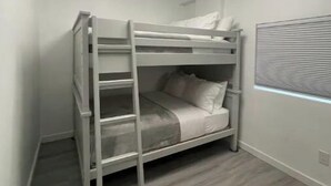 A bunk bed with a ladder in a room with light-colored walls and wooden flooring. - Beach Rental 3 Blocks to Beach! WIFI, Cable, A/C, and More! (San Diego)