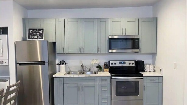 A modern kitchen with light grey cabinets, stainless steel appliances, and a sign on the fridge. - Beach Rental 3 Blocks to Beach! WIFI, Cable, A/C, and More! (San Diego)
