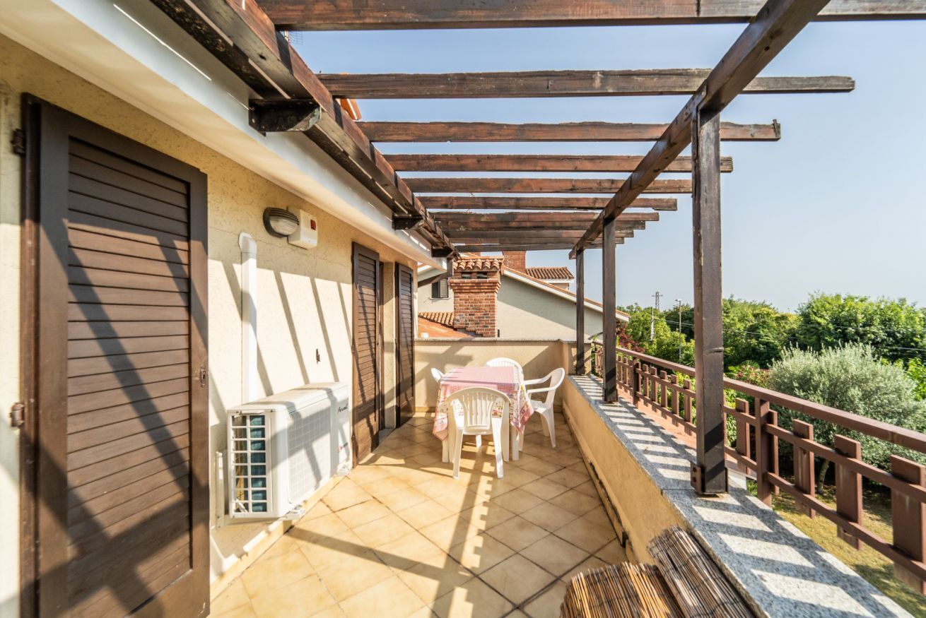 Un espacio al aire libre techado con patio, una mesa y sillas, una pérgola de madera y vistas a la vegetación.