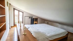 Ein Schlafzimmer mit einem hölzernen Bett, einem Nachttisch, einem Sessel und einem Fenster mit Blick.