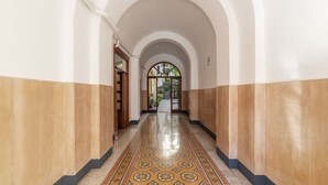 A hallway with a tiled floor, white walls, and an arched ceiling.