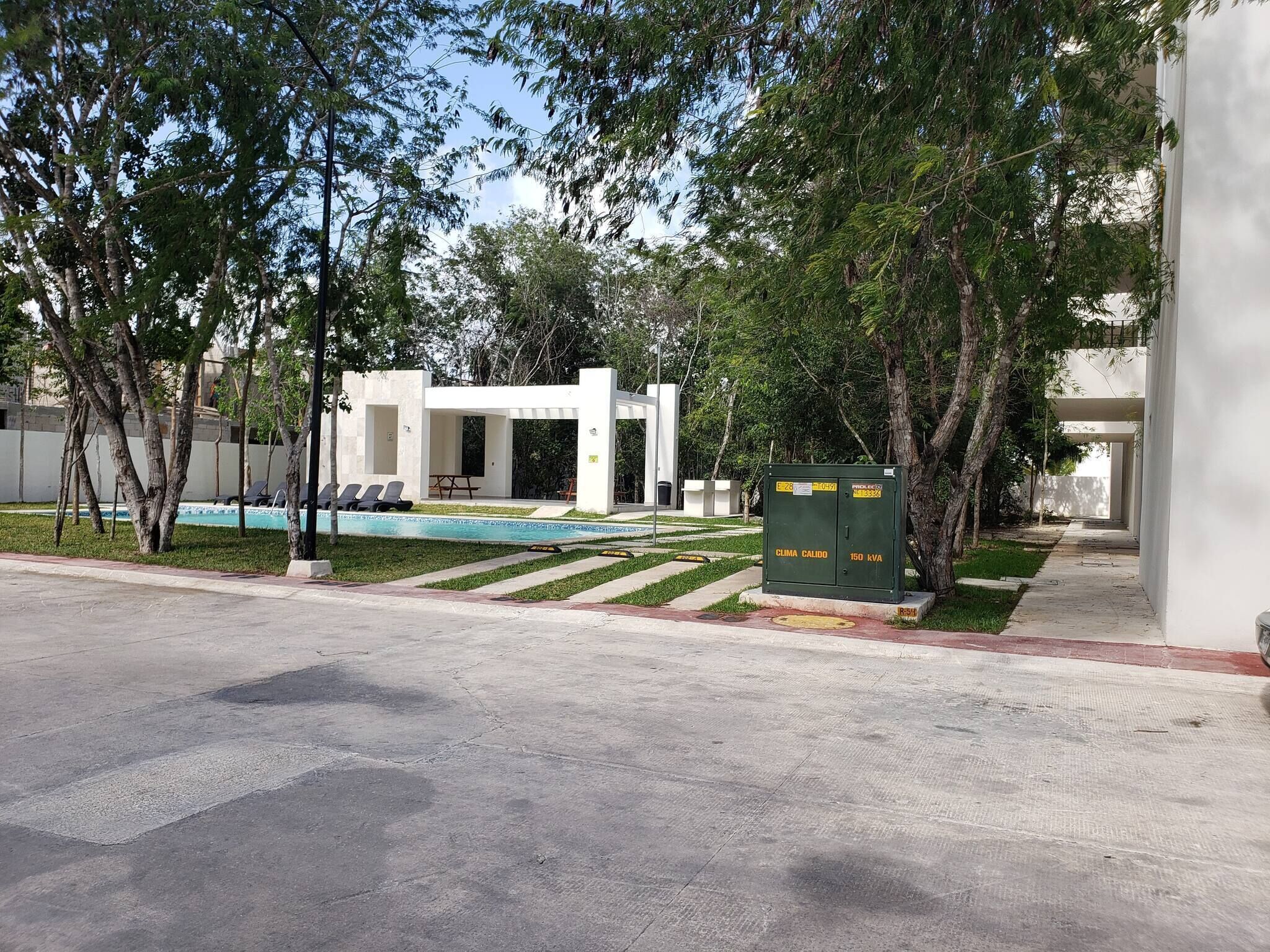 Un área de piscina con sillones de descanso, un pequeño pabellón y un cuarto de servicios.