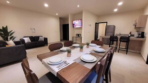 Ein modernes Wohnzimmer mit Essbereich, einer Küche und einem an der Wand montierten Fernseher.